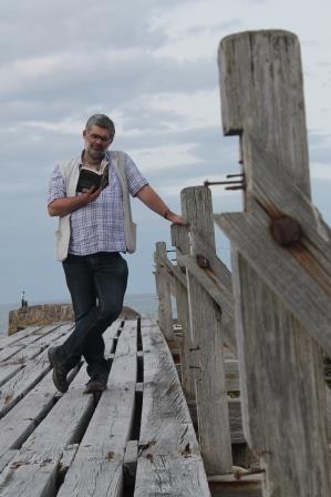 Ian Preston standing on a jetty at Lossiemouth reading a book